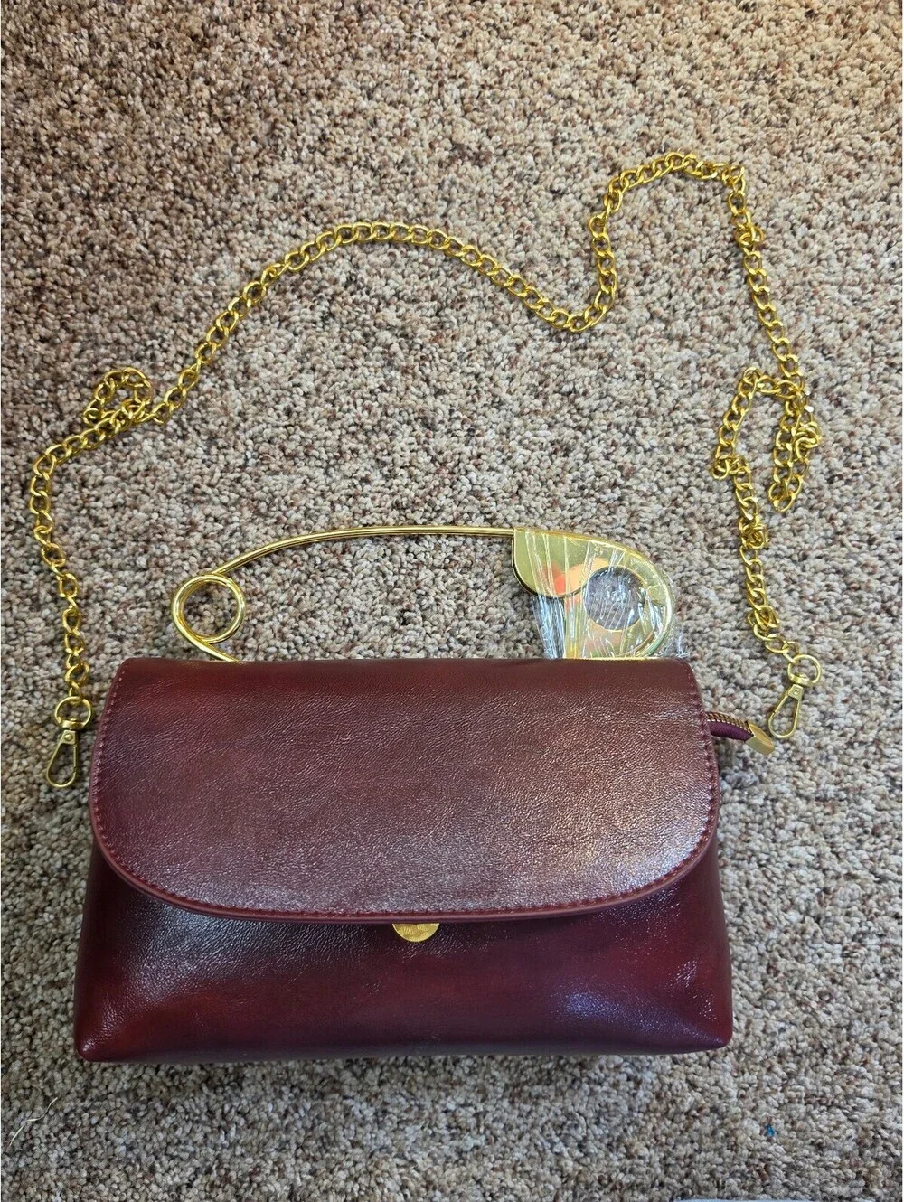 Elegant Burgundy Faux Leather Clutch Bag with Gold Chain and Safety Pin Detail
